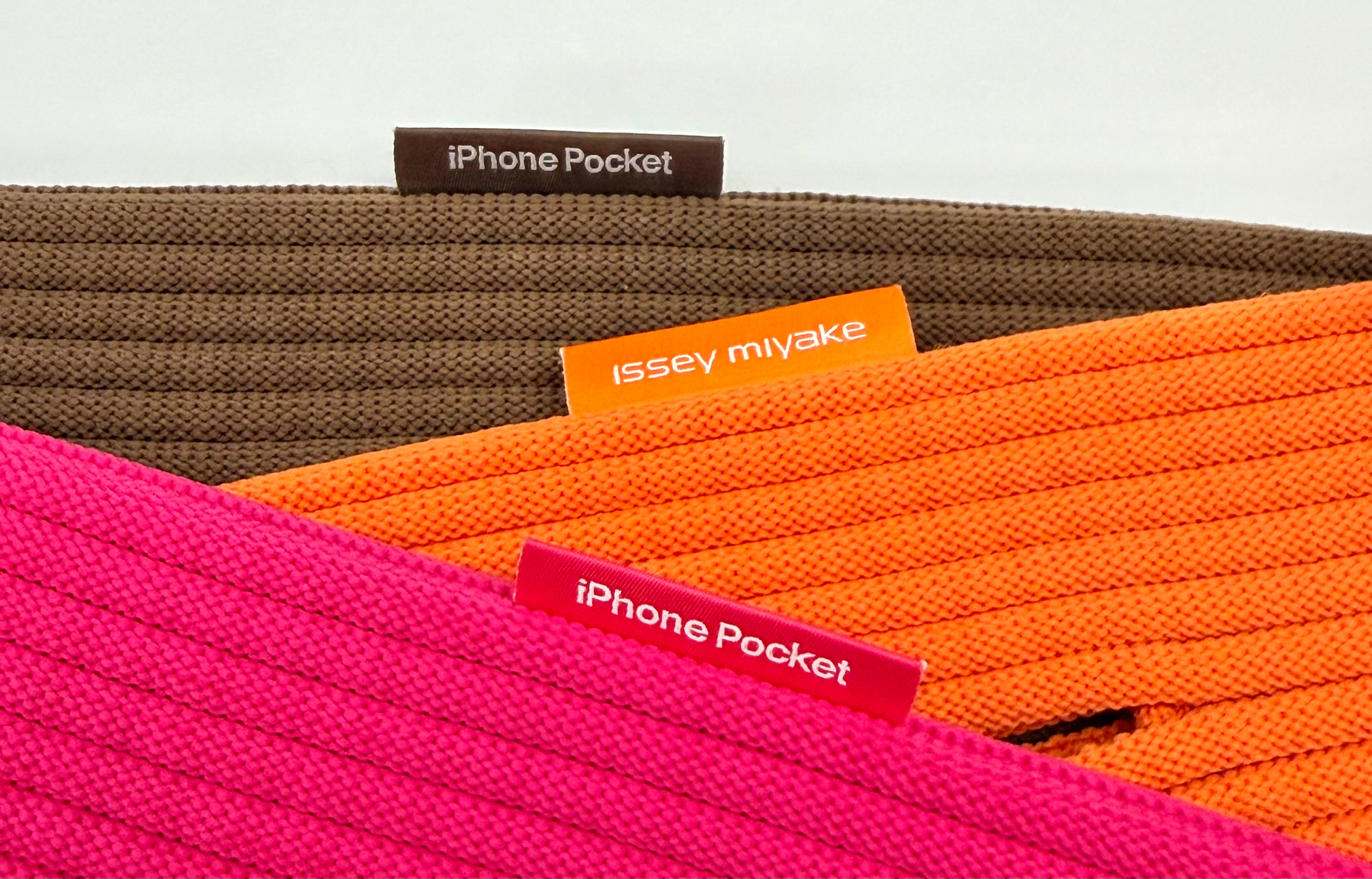Colorful textile items featuring labels with the words iPhone Pocket and Issey Miyake.